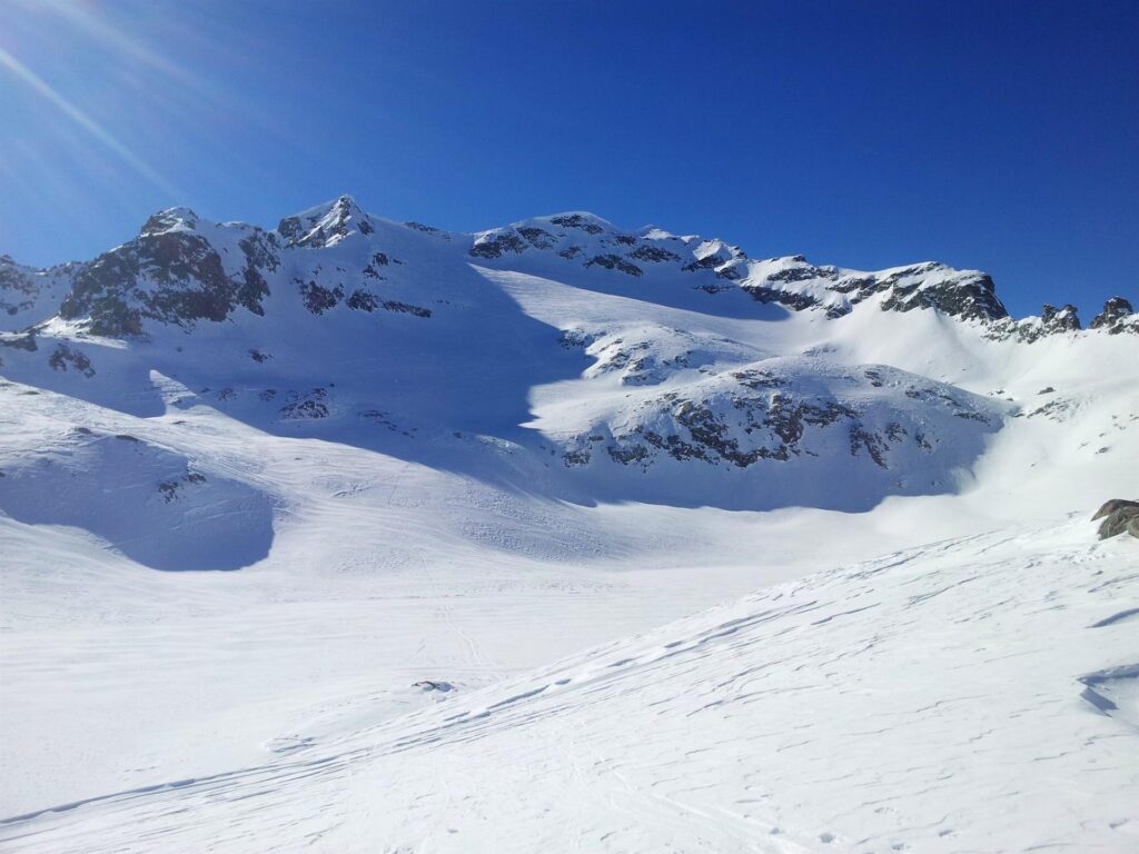 Ecco finalmente il lago alpino, totalmente coperto di neve e tranquillamente attraversabile. Sullo sfondo, la nostra cima e l'ultimo pendio pendente che dobbiamo risalire Ecco finalmente il lago alpino, totalmente coperto di neve e tranquillamente attraversabile. Sullo sfondo, la nostra cima e l'ultimo pendio pendente che dobbiamo risalire