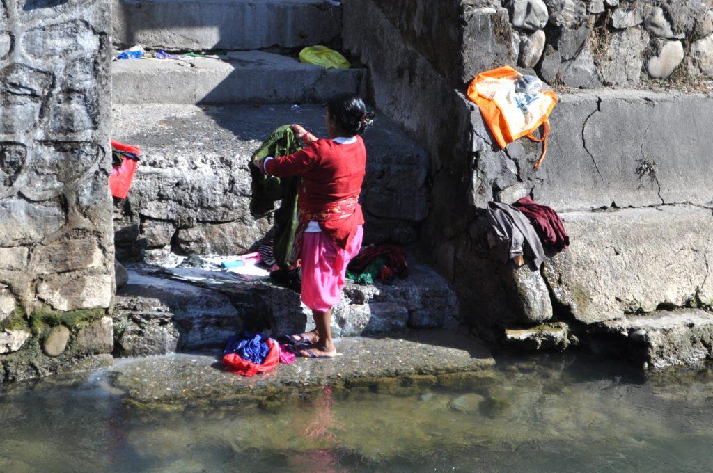 una donna lava i panni in un corso d&#039;acqua (ovvero: i colori non conoscono miseria)