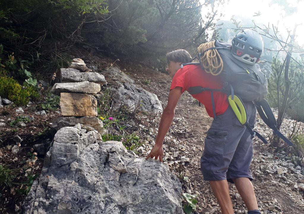 il grosso ometto che individua la traccia che sale ripida verso le pareti della torre