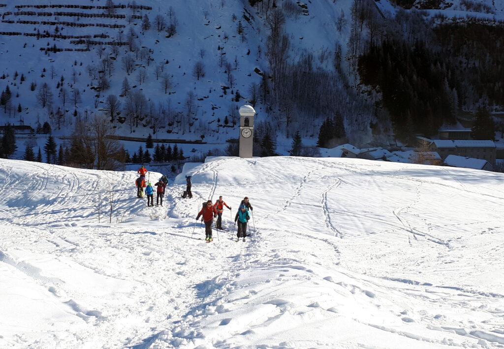 il campanile della chiesa di Isola svetta sulla neve, mentre il folto gruppetto si approssima a partire