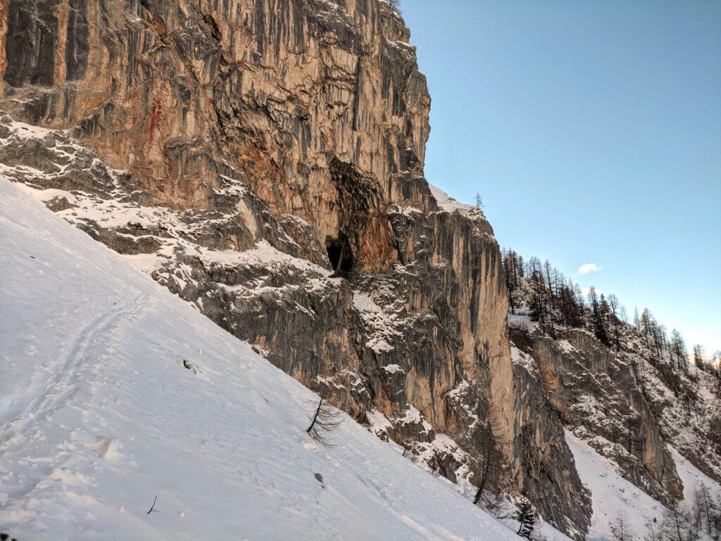 una delle grotte delle pareti nord della Val Gelada: la traccia invernale passa molto vicina alle rocce, mentre quella estiva tutta sul lato opposto
