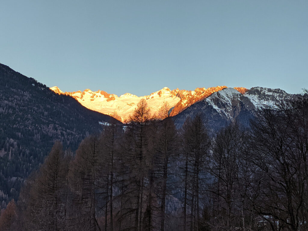 il primo sole inizia ad illuminare il versante opposto della Val Rendena, infuocando le cime