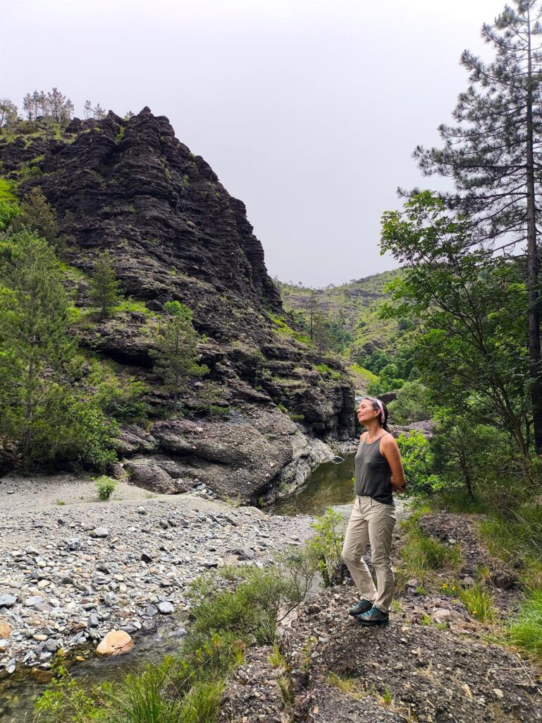 Erica vicino al torrente si guarda attorno osservando le formazioni rocciose