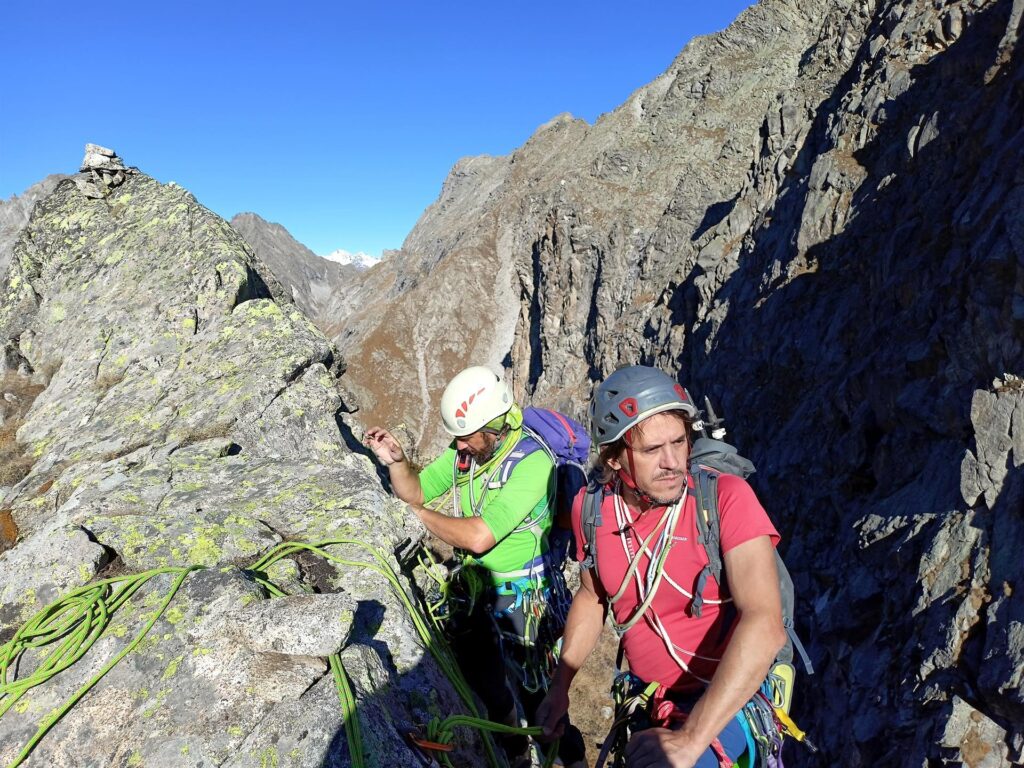 Arrivati in cima, si individua uno spit che può essere usato per far sicura ai secondi di cordata durante la discesa verso la seconda forcella