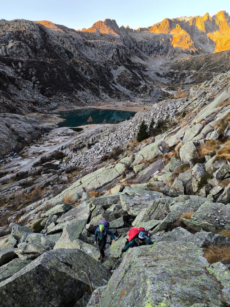 La salita tra pietraie per raggiungere il primo risalto, con il lago di Cornisello sullo sfondo