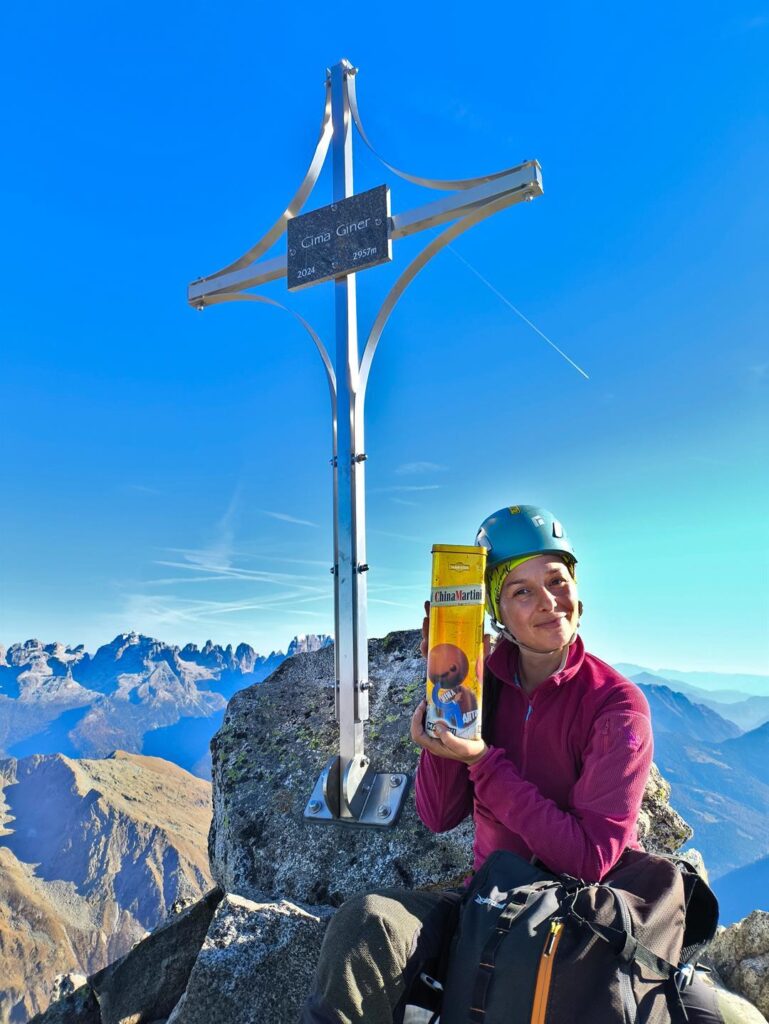 Erica felice con la croce nuova nuova della Cima Giner e il contenitore del libro di vetta
