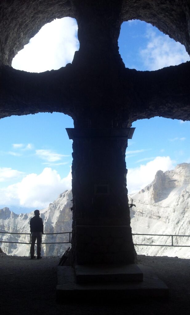 La grotta vista dall'interno, con l'enorme croce scavata che d&agrave; sul panorama circostante. Sulla sinistra, Ivana scruta l'orizzonte dalla grotta