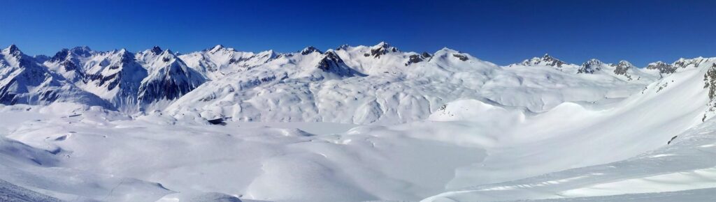 Siamo vicini al passo che dobbiamo raggiungere. Panoramica verso valle, con il lago dell'Enel bello innevato e le cime italiane della val Formazza