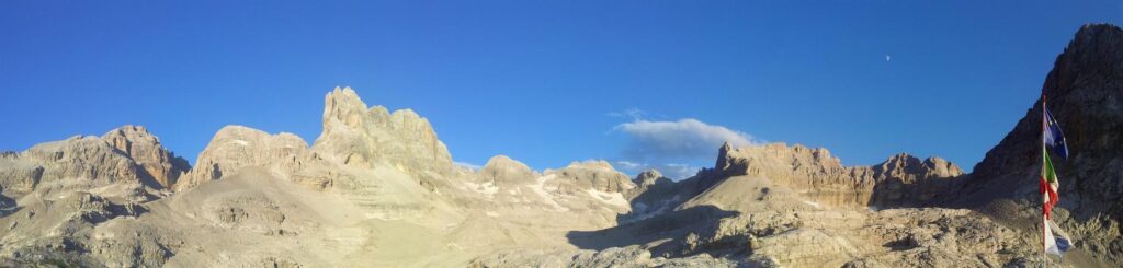 panoramica dal rifugio con le cime d'Agola nel mezzo, e le bandiere del rifugio sulla destra, poco prima del tramonto