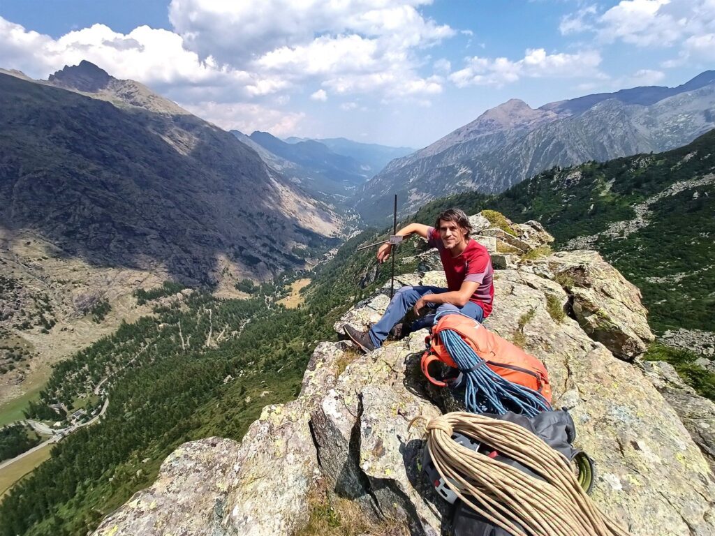 Gabri abbraccia la piccola croce di vetta: dietro la luuuuunga Val d'Ala