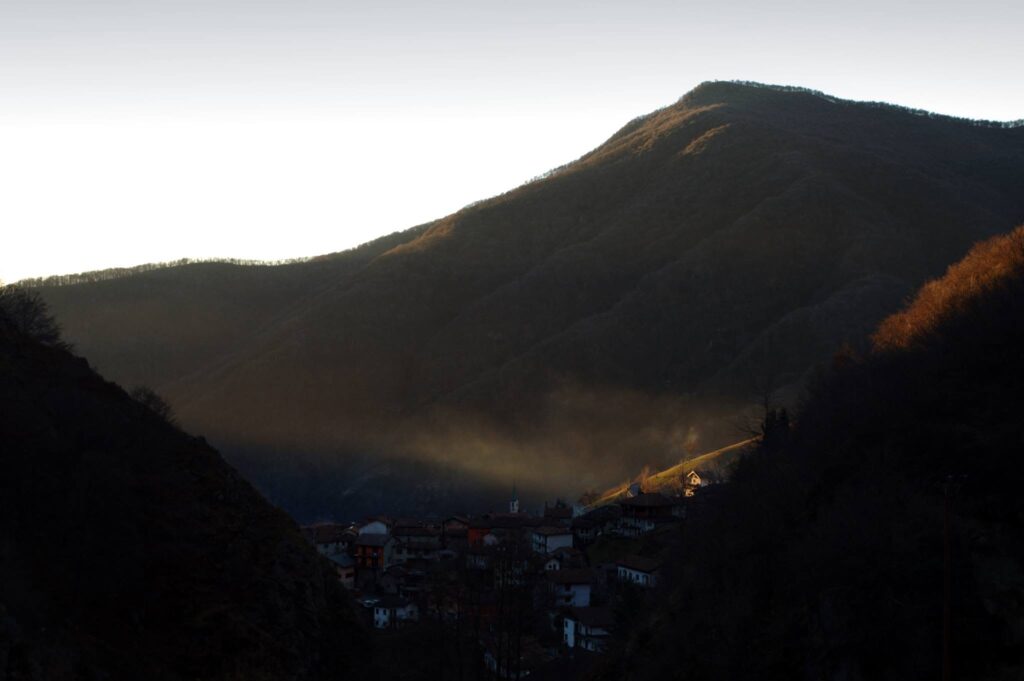 Luzzogno all'alba: l'ultima nebbia si alza e il borgo si prepara ad essere baciato dal sole. Da qui (di salite al Massone ce ne sono parecchie) fino all'alpe Colle il sentiero &egrave; stato inglobato in una strada consortile in parte asfaltata, che sale ad ampi tornanti. Per intrattenere i viandanti ci hanno piazzato una via crucis.